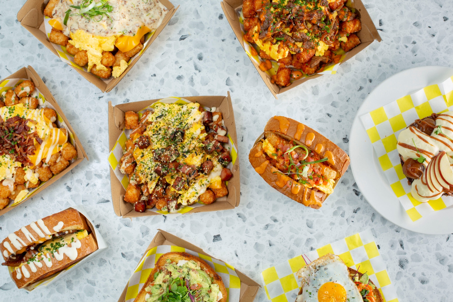 Toast & Yolk flat-lay — branded takeout box, avocado toast, and signature breakfast plates